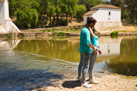 beautiful woman and handsome man latinos dancing bachata are dancing by the river in the forest. The couple do different postures while dancing. Dancing concept and expressions.の写真素材