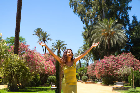 Beautiful young woman with long hair raises her arms to the sky giving thanks to life and the universe. The woman is happy and closes her eyes raising her head upwards. Concept of peace and happiness.の写真素材