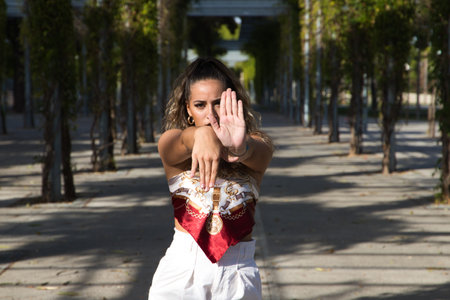 Latin woman, young and beautiful dancing modern dance on the street in a park and makes different expressions and postures. Concept dance, hip hop, dance, art, action, beauty, youth art.の写真素材