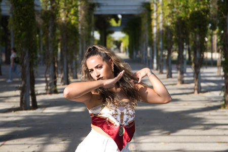 Latin woman, young and beautiful dancing modern dance on the street in a park and makes different expressions and postures. Concept dance, hip hop, dance, art, action, beauty, youth art.の写真素材