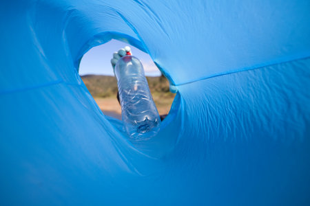Detail of a volunteer's hand putting a plastic bottle in the bag. Photo taken from below. Concept of Earth Day and World Environment Day June 5.の写真素材