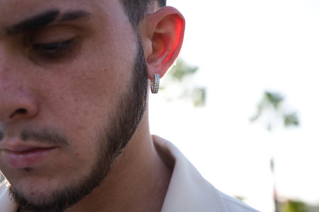 ear detail of young latin man earring with small diamonds. Fashion concept and male trend.の写真素材