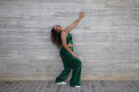 Latin woman, young and beautiful dancing modern dance on a background of gray cement in the street makes different expressions and postures. Concept dance, hip hop, dance, art, action, youth art.の写真素材