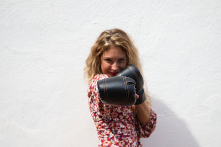 Cute young woman with boxing gloves and white top makes different gestures and expressions on white background. Woman is having fun. Concept claims.の写真素材