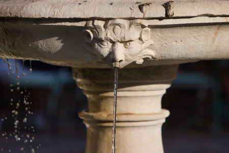 Stone fountain from which crystal clear water spurts out of a non-human head. Seville, Spainの写真素材