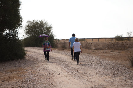 Three hikers walking along a rural path. Photo taken from behindの写真素材