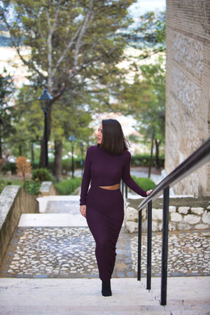 pretty young woman dressed in elegant purple dress climbs the stairs of the park holding on to the metal railing with her hand. The woman makes different expressions and gesturesの写真素材