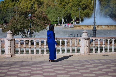 young and beautiful moroccan woman in blue abaya, typical arabian costume, walking along the canal in the square of spain in Seville, on a sunny day. travel conceptの写真素材