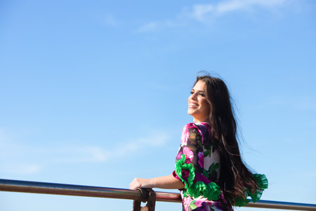 Young woman dancing flamenco with her hair in the air on the railing. On the horizon the Atlantic Ocean. Woman in white dress with ruffles and flowers typical of Andalusiaの写真素材
