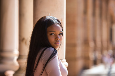 Portrait of an unhappy and sad African woman looking at the camera between marble columns.の写真素材