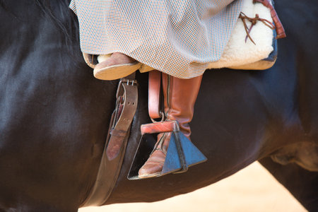 Detail of the boots of a woman in the stirrups riding a black horse of pure Spanish breed in Andalusia, Spainの写真素材