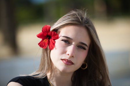 Portrait of a young, beautiful blonde woman with makeup and a red hibiscus flower in her hairの写真素材