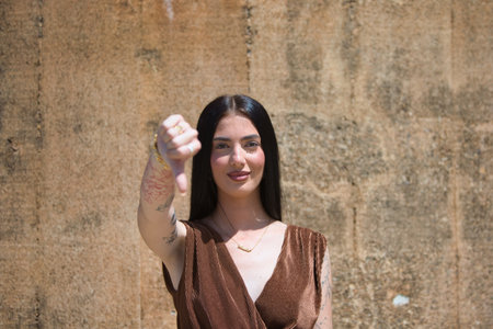 Young Latin woman looking at the camera, giving a thumbs down gesture of disagreement and disapprovalの写真素材