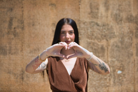 Young Latin woman looking at the camera, making a heart shape with her hands. Concept loveの写真素材