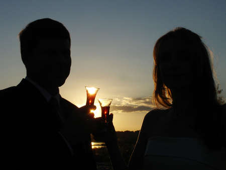            Silhouette of bride and groom having a drinkの写真素材