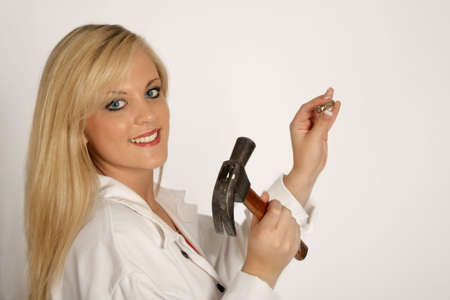A woman hammering a nail into the wallの写真素材