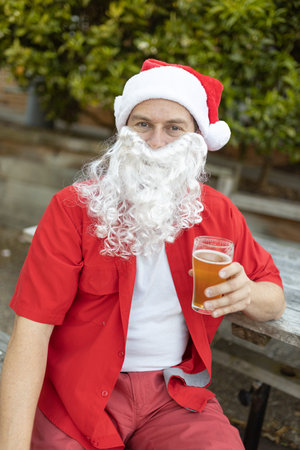 A Santa Claus at Christmas time in  the Australian summer holding a beerの写真素材