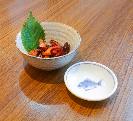 Seasoned Baby Octopus  and fish dish on wood tableの写真素材