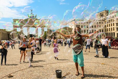Berlin, Germany - July 13, 2018: Street entertainer playing colorful soap bubbles among the crowd in front of the Brandenburg Gate in Berlin.のeditorial素材