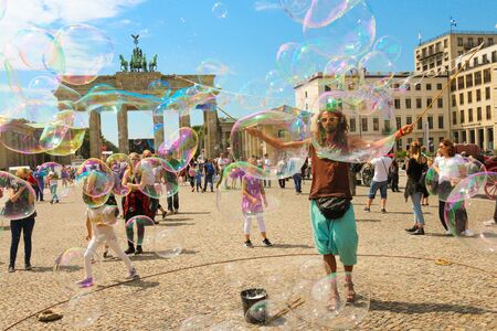Berlin, Germany - July 13, 2018: Street entertainer playing colorful soap bubbles among the crowd in front of the Brandenburg Gate in Berlin.のeditorial素材