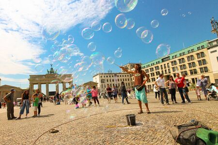 Berlin, Germany - July 13, 2018: Street entertainer playing colorful soap bubbles among the crowd in front of the Brandenburg Gate in Berlin.のeditorial素材
