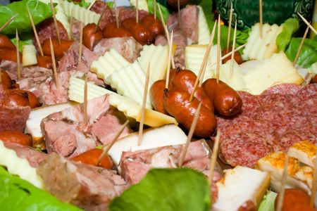 Sausage, slices of salami, bacon, ham and cheese on toothpicks