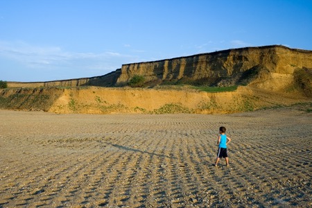 Little boy in sunset against big space and landの写真素材