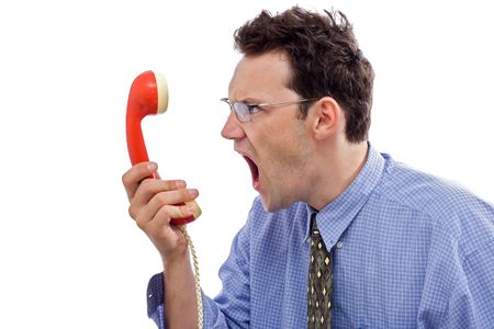 Angry businessman yelling loud in red telephone handsetの写真素材