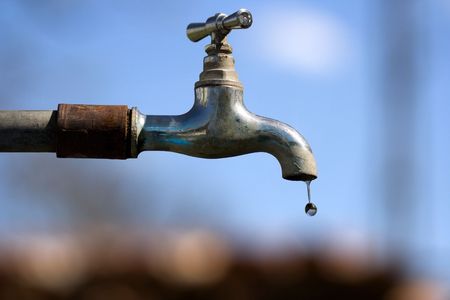 Water drop falling from an old tapの写真素材