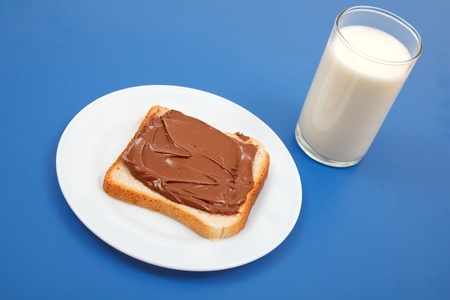 Bread slice with chocolate cream on plate and a glass of milkの写真素材