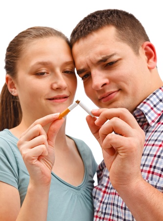 Young couple breaking apart cigarette, meaning stop smoking. Warning: focus on cigarette!の写真素材
