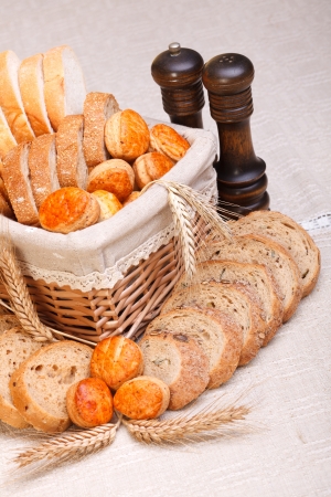 Assorted bakery products sliced, arranged in small basket. Wheat ears in front, salt and pepper behindの写真素材