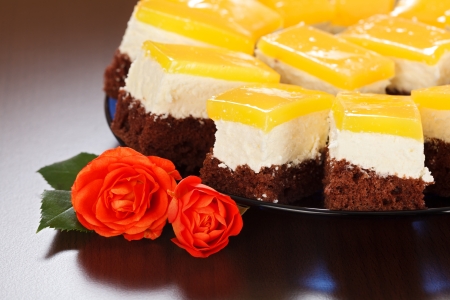 Closeup view of three-layered yoghurt cakes with red roses on brown backgroundの写真素材