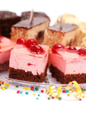 Closeup view of various creamy cakes  on plate with colorful small candies aroundの写真素材