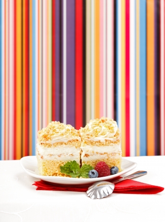 Whipped cream cake garnished with berries in front of colorful striped background - copy space aboveの写真素材