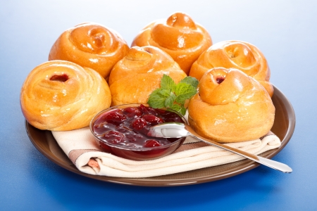 Lots of sour cherry cakes and jam on plate, blue backgroundの写真素材