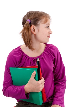 Teenager girl looking right, holding folders and pencils in her hand isolated on white background の写真素材