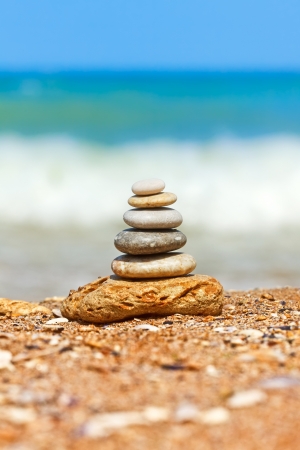 Differently sized and colored pebbles stacked, the sea in the backgroundの写真素材