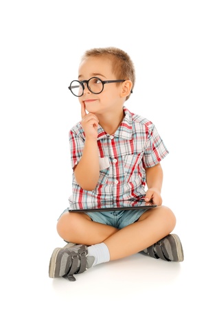 Wise little boy thinking, wearing big glassess and holding tablet pcの写真素材
