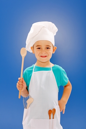 Little chef showing wooden spoon on blue backgroundの写真素材
