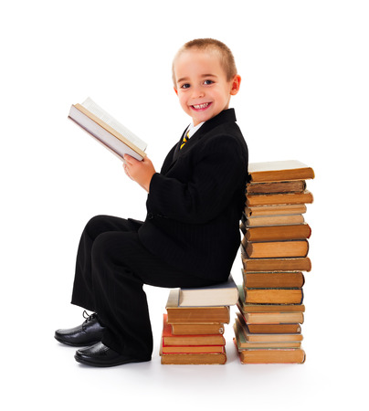 Portrait of a funny little kid sitting on old books and readingの写真素材