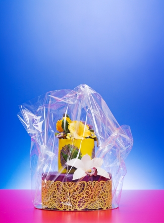 Colorful purple-yellow cake decorated with edible candy flowers and lace in cellophane wrapの写真素材