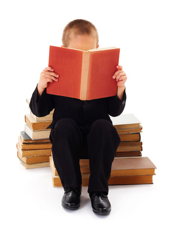 Kid with book in hand sitting and enjoying readingの写真素材