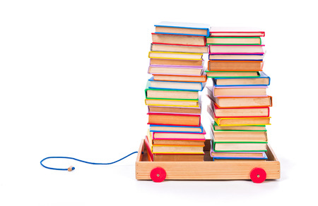 Little toy cart full of stacked, colorful booksの写真素材