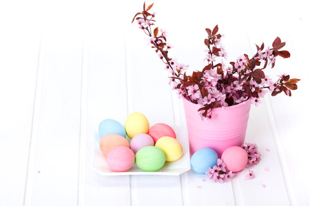 Easter arrangement with peach flowers in pink pail and pastel colored eggs