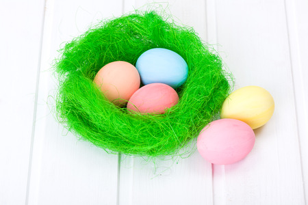 Easter eggs in green nest on white boardの写真素材