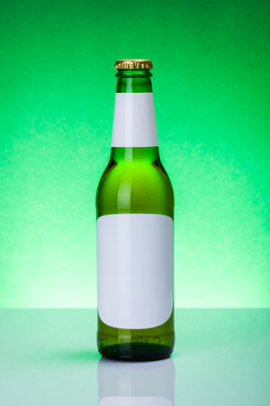 Green beer bottle with blank labels on elegant, backlit backgroundの写真素材