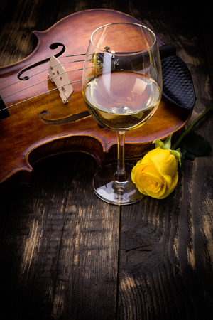 Violin, wine and yellow rose on dark wooden backgroundの写真素材