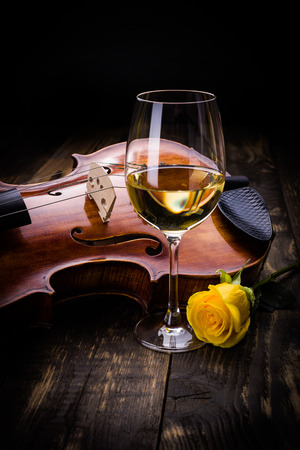 Violin, wine and yellow rose on dark wooden backgroundの写真素材
