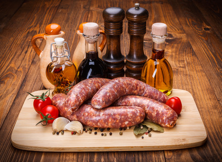 Pork sausages on cutting board with spicy oil bottlesの写真素材